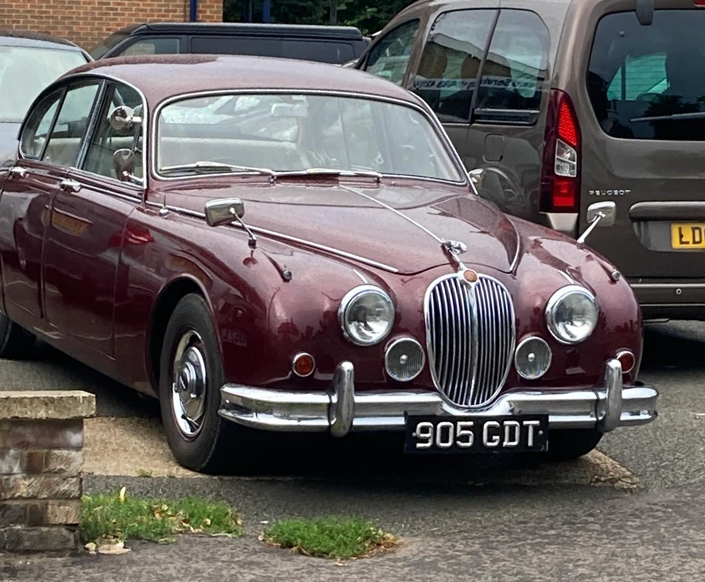 A 1962 Jaguar (car) on a garage forecourt.  The colour is registered as 'red' but I'd call it 'maroon'